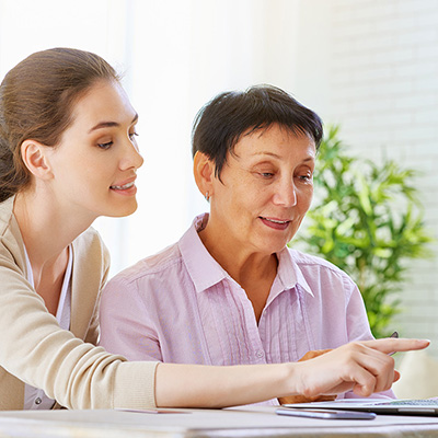 caregiver assisting elderly woman on her laptop