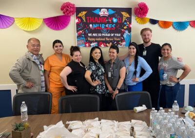 A group of employees standing behind a table with sandwiches and water bottles at Willows Post Acute.