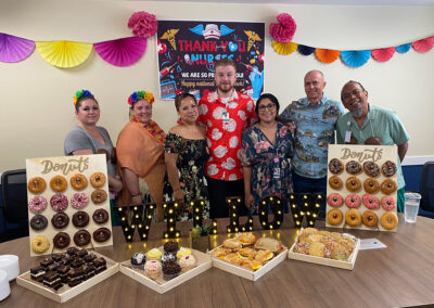 A group of employees standing behind a table full of donuts at Willows Post Acute