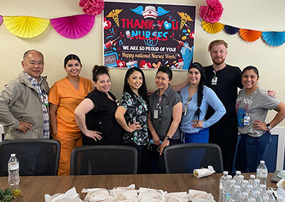 A group of employees standing behind a table with sandwiches and water bottles at Willows Post Acute.