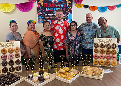 A group of employees standing behind a table full of donuts at Willows Post Acute
